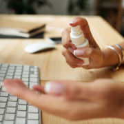 Woman at desk using hand sanitizer: how to create a healthy workplace environment