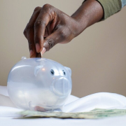 Person putting money into a piggy bank.